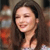 A static pixelated image of a person with long dark hair, closed eyes, and a slight smile, wearing a light-colored top against a blurred background.