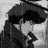 Black-and-white pixelated image of a person with dark hair styled in an updo, wearing a high-collared garment and holding a small object near their mouth.