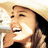 A pixelated image of a person wearing a light-colored cowboy hat, smiling broadly with mouth open and teeth visible.