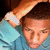 A person in a light blue shirt with a white wristband raises their arm above their head, captured in a static image with no visible motion.