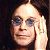 Pixelated close-up of a person with light skin, dark hair, and blue-tinted glasses resting on their head against a dark background.