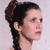 Pixelated close-up of a person's head and neck with dark hair styled in a high ponytail, light skin, and a neutral expression against a pale background.