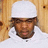 A pixelated static image shows a person wearing a white cap and white clothing against a light brown wooden background.