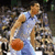 Pixelated image of a basketball player in light blue jersey holding an orange ball, with text overlays on adjacent