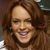 A static pixelated image shows a person with long brown hair smiling, wearing a dark top against a blurred background.