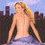 A pixelated image of a woman with long blonde hair wearing blue jeans, standing against a cityscape background on the left side, next to green text reading "Original Icons .com" on a dark green background on the right side.