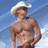 Pixelated image of a shirtless man in a cowboy hat against a blue sky, with red text on a yellow background announcing a concert and date.