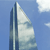 Pixelated static image of a tall, modern building with a curved facade against a clear blue sky with faint clouds.