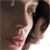 Pixelated static image of a person's lower face and neck with visible skin tones, dark hair, and pink lips against a brown background.
