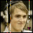 A person with light brown hair wearing over-ear headphones, smiling slightly while facing left in a of six