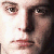 Pixelated close-up of a person's face showing eyes, nose, and mouth with light skin tones and dark hair against a bright background.