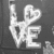 Four grayscale display love-themed symbols: a neon-style 'LOVE' with heart-shaped O, interlocked hands, a tattooed heart outline, and handwritten text reading "It's Love" with a heart symbol
