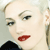 Pixelated close-up of a person with light skin, dark eyebrows, and red lips, wearing a dark top against a light background.