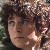 Pixelated close-up of a person with dark curly hair and light skin, wearing a dark top against a blurred background.