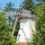 A pixelated outdoor scene shows a white bird with a red beak standing among green foliage under a blue sky.