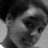 Black-and-white pixelated image of a person's face with dark hair, visible eye, nose, and mouth against a light background.