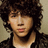 A pixelated image shows a person with curly dark hair on the left, next to a pink background with blue text and symbols.
