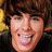 Pixelated close-up of a person with brown hair and light skin smiling broadly, showing teeth, against dark background with yellow accents.