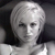 Pixelated grayscale image of a person with short light-colored hair, neutral expression, and dark background, cropped to show upper torso.