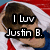 A person with brown hair wearing a red and white striped hooded garment and blue clothing, with text overlay reading "I luv Justin B." in black block letters.