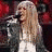 Pixelated image of a person with long light brown hair singing into a microphone, next to a pink star with text.