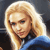 Pixelated close-up of a person with long blonde hair wearing a blue garment against a dark background.