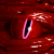 A red, textured surface with a vertical slit-like opening bordered by pink and white highlights on the left side of the frame.