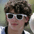 A person with brown curly hair and white sunglasses appears in a of four , with the rightmost showing a gray background