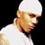 Pixelated close-up of a person wearing a white head covering and white shirt against a black background.