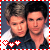 Two identical figures in dark blue shirts with white collars stand side-by-side against a gray background, framed by red and white checkered borders.