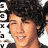Pixelated static image of a person with dark curly hair, light skin tone, and closed eyes smiling slightly against white background.