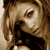 Pixelated close-up of a person's face with brown hair and dark clothing, rendered in sepia tones on a light background.