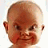 Pixelated close-up of a baby's face with smooth brown skin, dark eyes, and rosy cheeks against a light background.