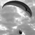 A grayscale image shows a curved dark shape above a lighter area with a small dark spot below, all on a pixelated background.
