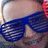 A pixelated image split into two sections: a person wearing blue shutter shades on the left and bold text on a red background on the right.
