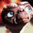 Animated sequence of a character with large blue eyes and textured skin, showing subtle head movement against a warm-toned background.