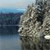 A pixelated static image shows a rocky cliffside with a body of water in the background under a light blue sky.