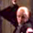 Static 48x48 pixel icon showing a blurred figure with light hair and dark clothing against a muted background, rendered in low-resolution with visible dithering and color bleeding.