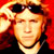 Static pixelated image of a person with sunglasses on head, red background, and visible facial features including eyes, nose, mouth, and neck.