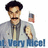 Pixelated image of a man with dark curly hair and mustache wearing gray jacket over light shirt, holding small object in right hand, blue text at bottom.