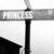 A grayscale street sign with the word "FRANKS" visible on a horizontal arm, mounted on a vertical pole against a light background.