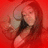 Pixelated image of a person with long red hair against a solid red background, wearing dark clothing and holding an object near their face.