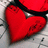 A red heart-shaped object with a black outline and visible cracks on its surface, set against a light gray background.