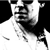 Black-and-white pixelated static image of a stylized human face with exaggerated features and motion blur effects, likely representing a character from a film or media franchise.