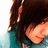 Pixelated close-up of a person with dark brown hair and light skin wearing a teal garment, cropped to show only the head and shoulders.