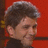 Pixelated close-up of a person's head and shoulders against a red background with dark vertical elements.