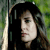 Pixelated profile view of a person with dark hair and light skin, wearing a dark top against a green and gray background.