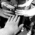 Black-and-white animation of hands clasping and unclasping in a circular motion against dark background.