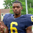 A pixelated image of a person in a dark blue football jersey with yellow number 6, standing outdoors with greenery in the background, next to text blocks on purple and gray backgrounds.