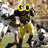 A football player in yellow and black uniform running with ball, surrounded by blurred opponents on a field.